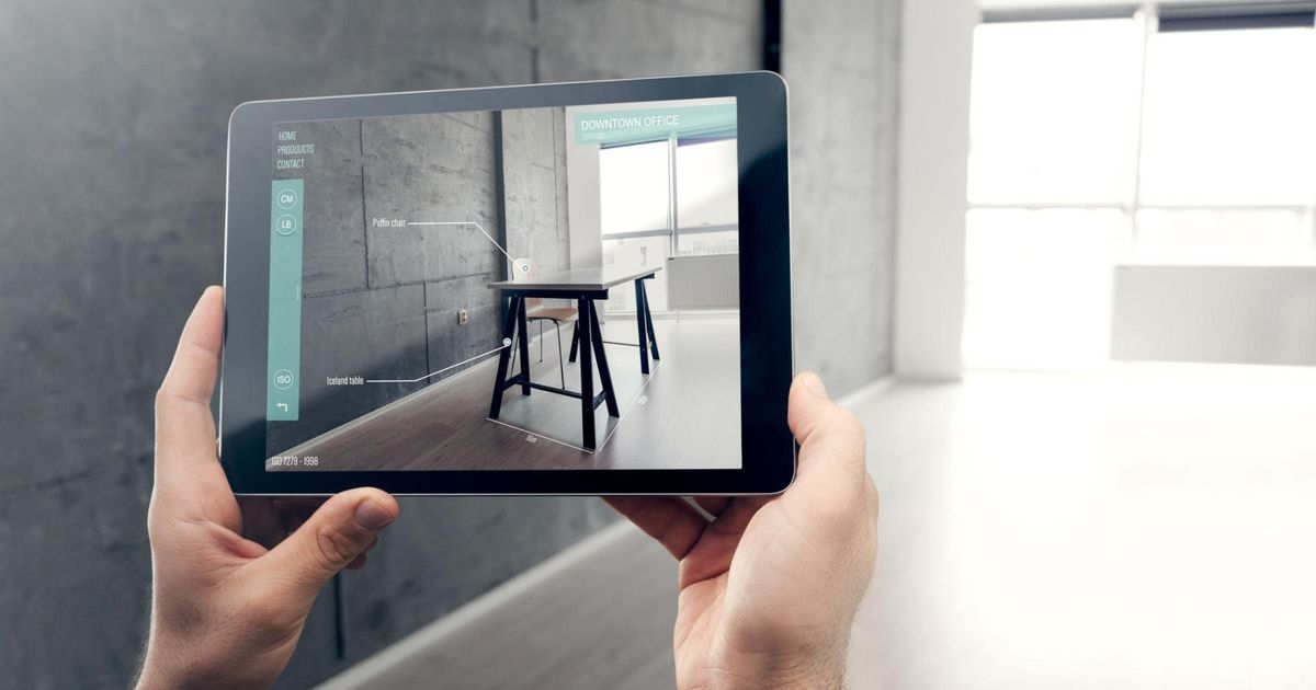 Augmented-Reality-Apps im Handel: So werden Produkte erlebbar POV: Zwei Hände halten ein Tablet, die App auf dem Display zeigt Möbel im Raum, der in der Realität leer ist